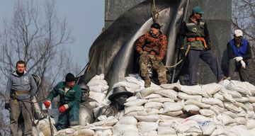 Warga menumpuk karung pasir di sekitar monumen penyair Ukraina Taras Shevchenko untuk melindunginya dari kerusakan akibat penembakan di Kharkiv saat serangan Rusia di Ukraina berlanjut, pada 25 Maret 2022.