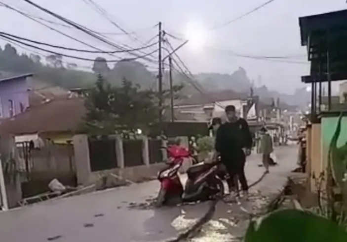 Dua pemuda menerobos jalan yang masih basah di Desa Langensari Lembang, Kabupaten Bandung Barat pada Minggu, 23 Juli 2023.