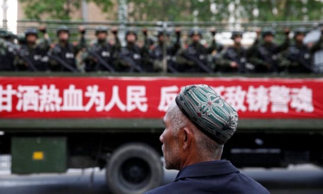 TRUK yang mengangkut rombongan militer China melintas di depan seorang pria etnis Uighur di Xinjiang.*/ANTARA