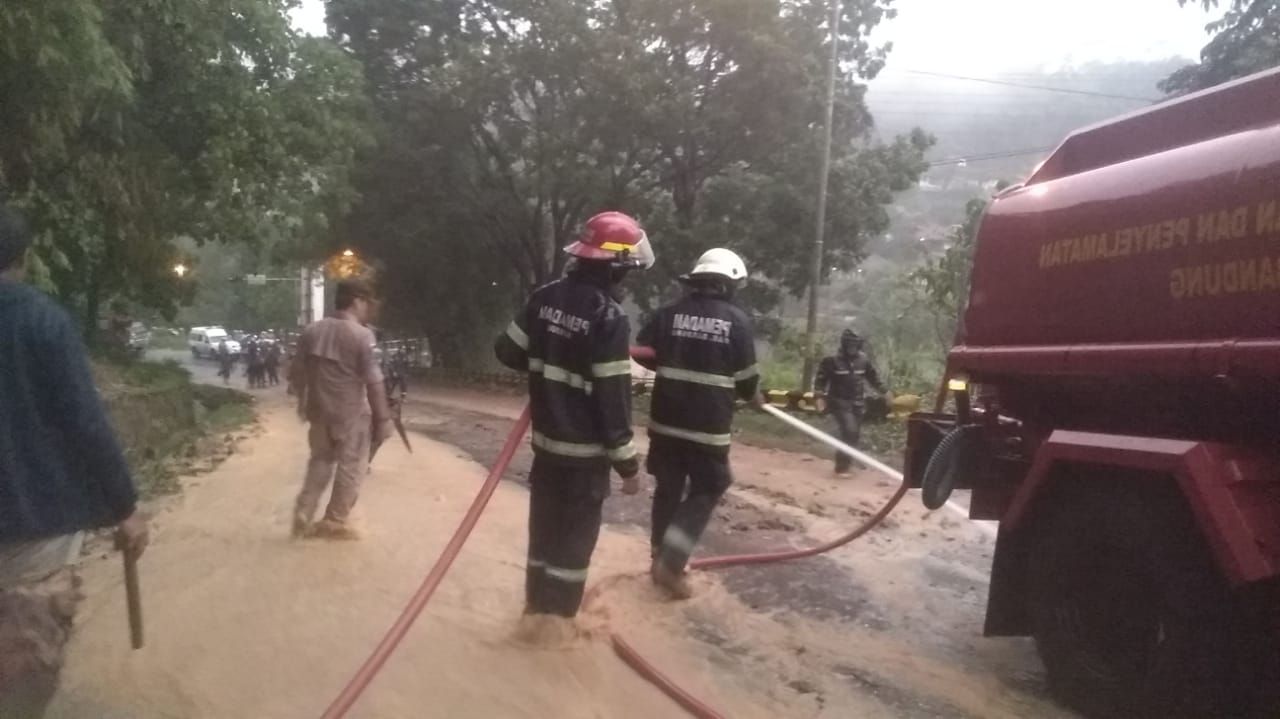 PETUGAS mengerahkan alat berat dan mobil pemadam kebakaran untuk membersihkan material longsor yang menutupi Jalan Raya Soreang-Ciwidey di Kampung Patrol, Desa Soreang, Selasa 17 Desember 2019.*
