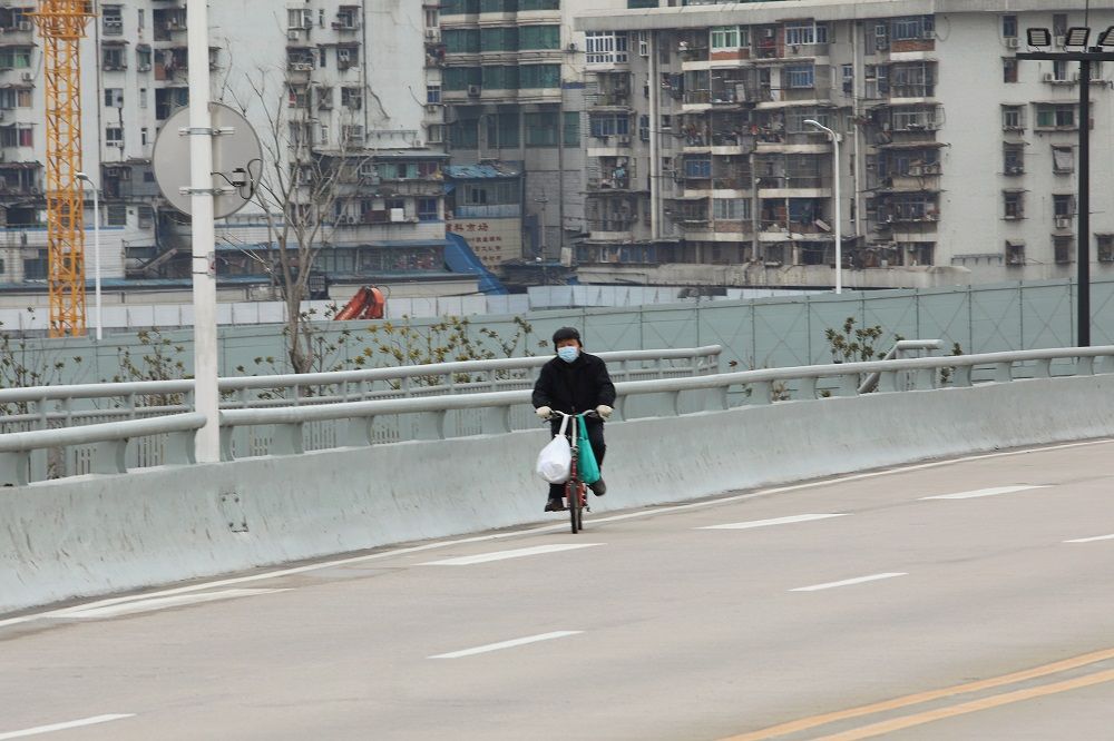WARGA memakai masker bersepeda di jalanan yang sepi di Wuhan, Provinsi Hubei, Tiongkok yang jadi pusat penyebaran virus corona, Jumat 7 Februari 2020.*