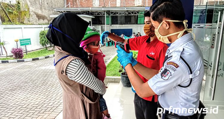 Petugas BPJS Kesehatan Kabupaten Bandung melakukan cek suhu tubuh dengan menggunakan thermal gun