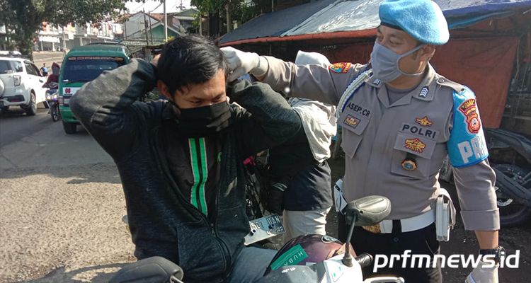 Seorang pegemudi ojek online saat diberhentikan petugas untuk menggunakan masker kain yang dibagikan kepolisian di kawasan Margaasih, Kabupaten Bandung, Kamis (9/4/2020).* BUDI SATRIA