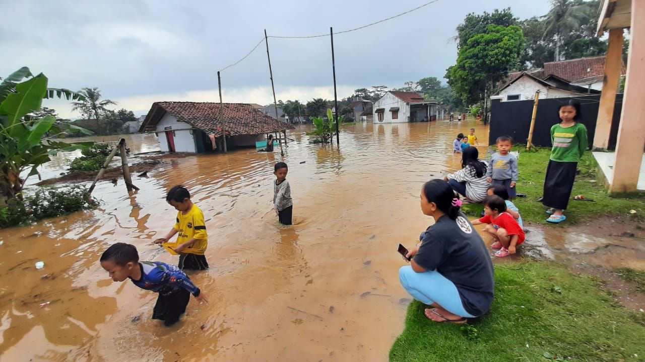 ANAK-anak bermain di tengah banjir yang menggenang jalan di Desa Tanjungsari, Kecamatan Sukaresik, Kabupaten Tasikmalaya, Rabu, 10 Juni 2020.*