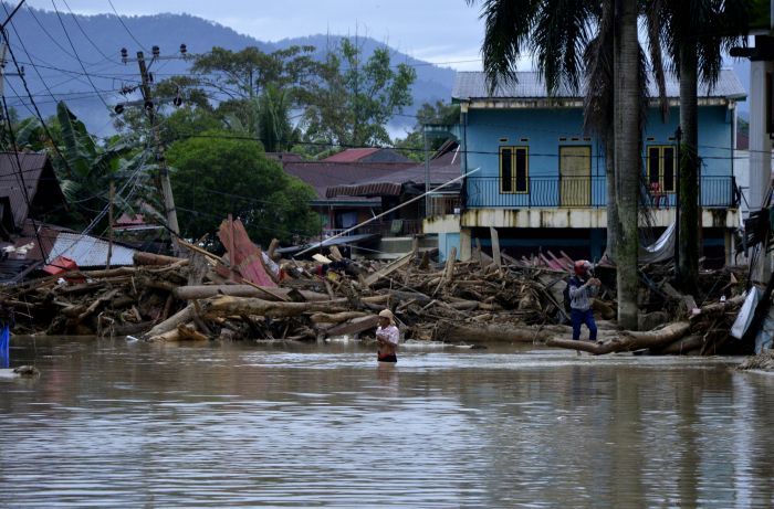 Warga melintas di sekitar rumah yang tertimbun lumpur dan batang pohon akibat terjangan banjir bandang di Kecamatan Masammba, Kabupaten Luwu Utara, Sulawesi Selatan, Rabu (15/7/2020). Banjir bandang yang terjadi akibat tingginya curah hujan tersebut mengakibatkan 16 orang meninggal dunia dan puluhan warga dilaporkan masih dalam pencarian, sementara ratusan rumah rusak berat dan hilang.ANTARA FOTO/Abriawan Abhe/aww.