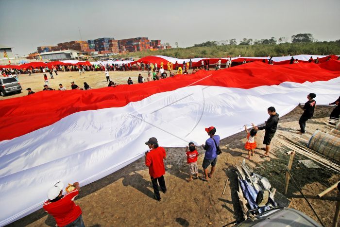 Warga membentangkan bendera Merah Putih saat memperingati Hari Sumpah Pemuda di kampung nelayan Greges, Surabaya, Jawa Timur, Minggu (27/10/2019). Peringatan Hari Sumpah Pemuda ke-91 di daerah tersebut dimeriahkan dengan pembacaan Ikrar Sumpah Pemuda di atas perahu, pembentangan bendera Merah Putih sepanjang 500 meter serta pentas kesenian dan berbagai perlombaan. ANTARA FOTO/Moch Asim/ama.