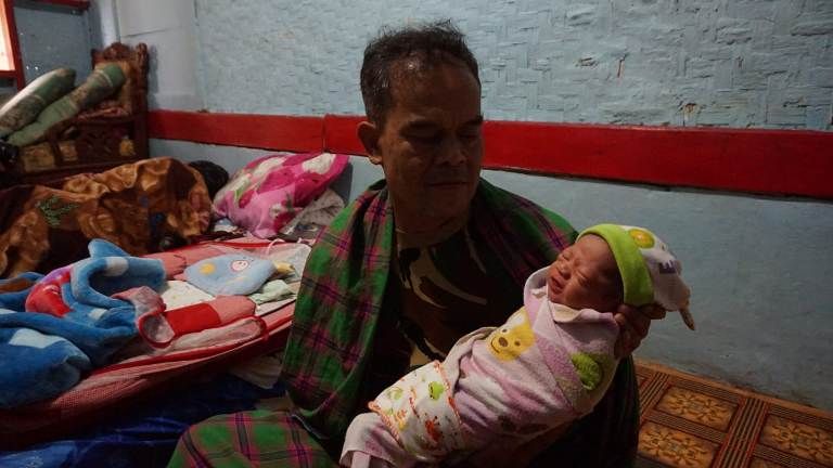  Mahmudin saat menggendong cucunya yang baru lahir di kediamannya di Mandalasari Kabupaten Tasikmalaya. (Septian Danardi)