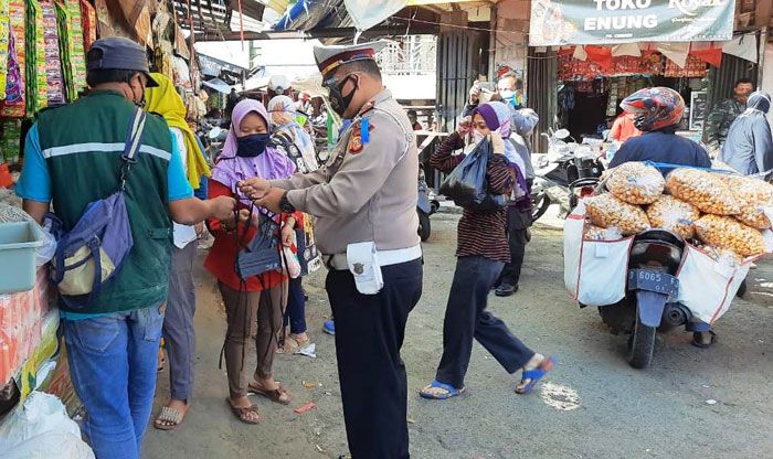 Kepala Bagian Operasi (KBO) Satuan Lalu Lintas Polres Cimahi, Iptu Duddy Iskandar dikerumuni warga saat bagikan masker. (Foto: Laksmi Sri Sundari/Galamedia)