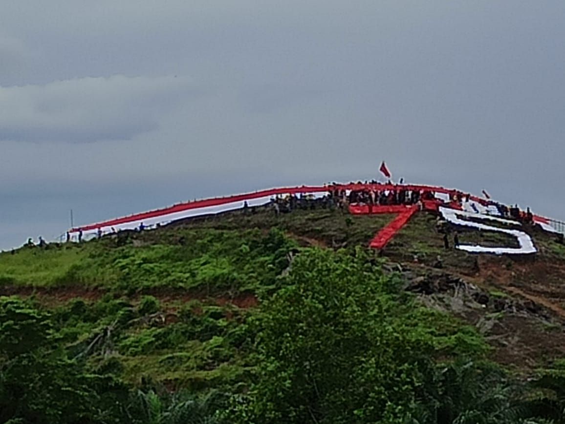 Pengibaran bendera merah putih dengan ukuran 75 meter oleh relawan dan pengungsi korban banjir bandang Luwu Utara /Istimewa.