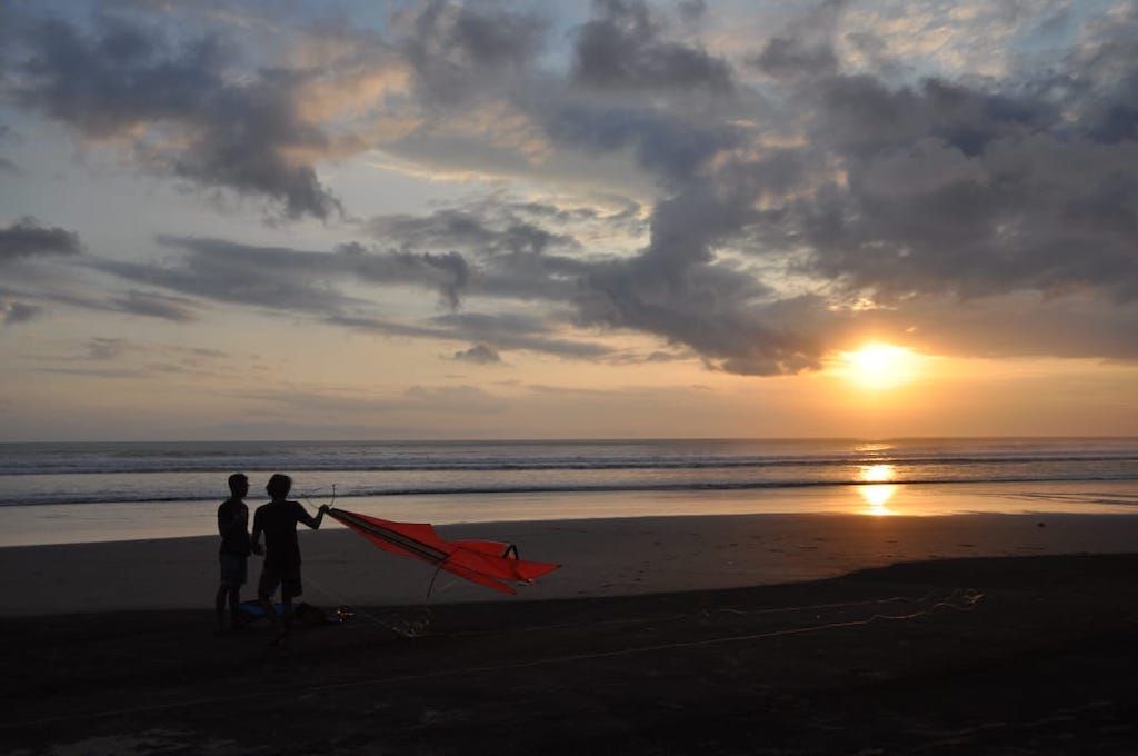 Menikmati indahnya Matahari terbenam di Pantai Seminyak Bali sambil bermain layang layang