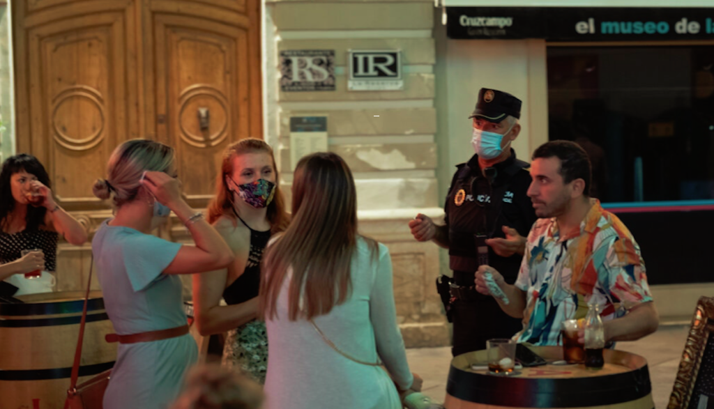 Petugas Kepolisian Spanyol mengawasi dan menegur pengunjung cafe yang kedapatan tidak menggunakan masker