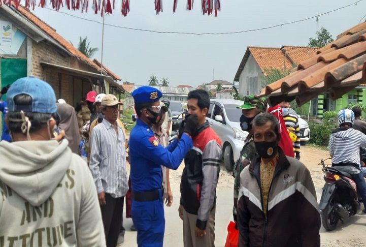 Bintara Pembina Potensi Maritim (Babinpotmar) Pos TNI AL Kronjo mengenakan masker kepada seorang warga di wilayah pelabuhan tradisional Kronjo, Kabupaten Tangerang, Jumat 11 September 2020.*