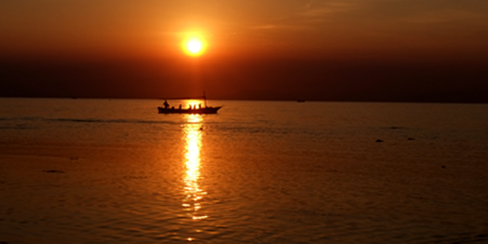 Perahu di tengah pantai berlatar sunset/ Frans Gandhi