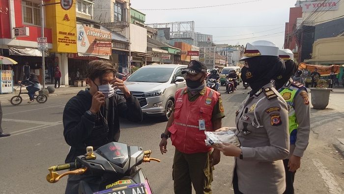 Polisi membagikan masker kepada pengguna sepeda motor yang kedapatan tak mengenakan masker, di kawasan Jalan Ahmad Yani, Kota Bandung, Jumat, 18 September 2020. (Remy Suryadie/Galamedia)