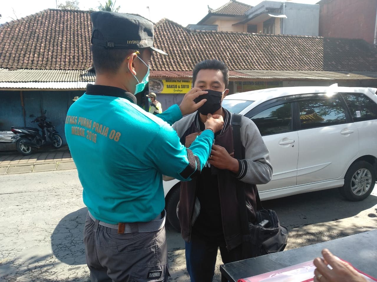 Petugas operasi prokes Polsek Mengwi Badung mencontohkan pemakaia masker yang benar kepada pengguna jalan agar disiplin mematuhi prokes guna menangkal penyebaran virus covid-19 di Bali