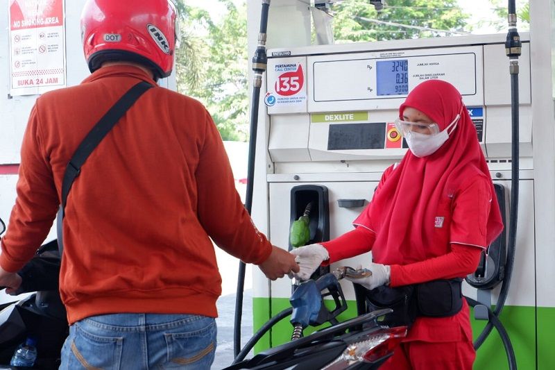 konsumen di Bali tengah bahan bakar kendaraan motornya dengan pelayanan petugas sesuai protokol kesehatan