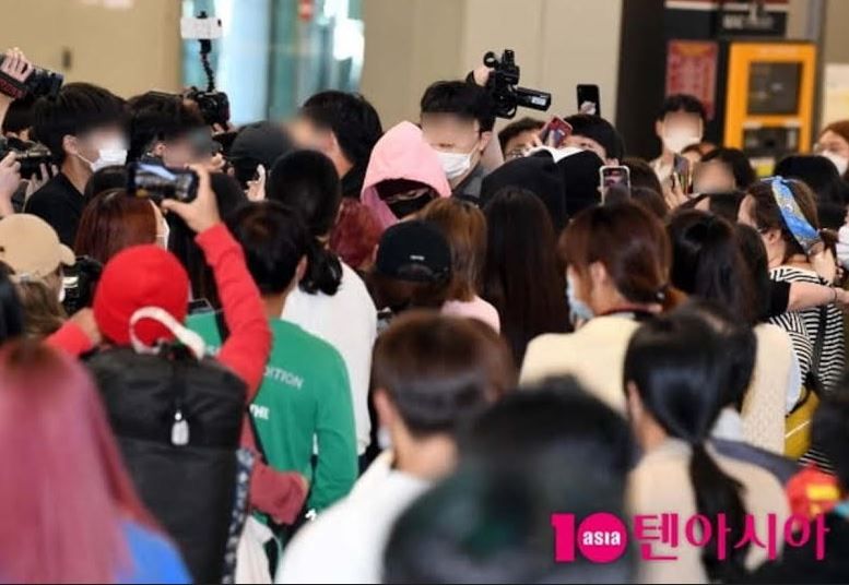 Heeseung ENHYPEN (menggunakan hoodie) di Bandara Gimpo di tengah banyak orang dan penggemar.