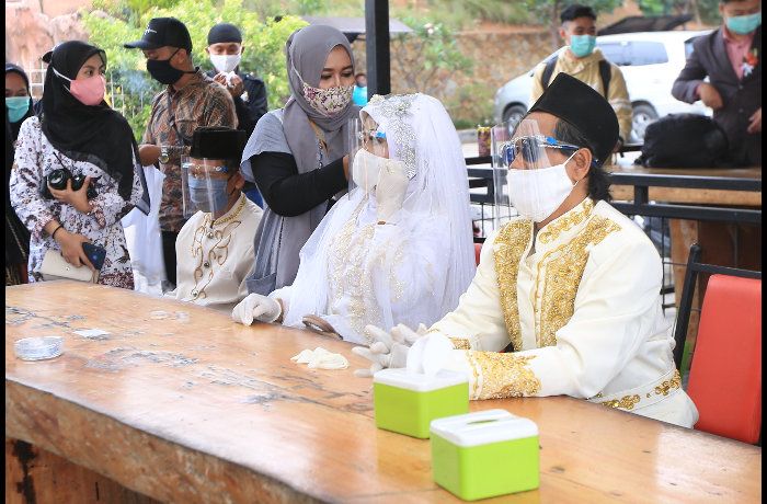 Sepasang pengantin mempersiapkan diri sesaat sebelum prosesi pernikahan masal di atas altar di ketinggian di area wisata Taman Love di Soreang, Kabupaten Bandung, Sabtu 26 September 2020. 