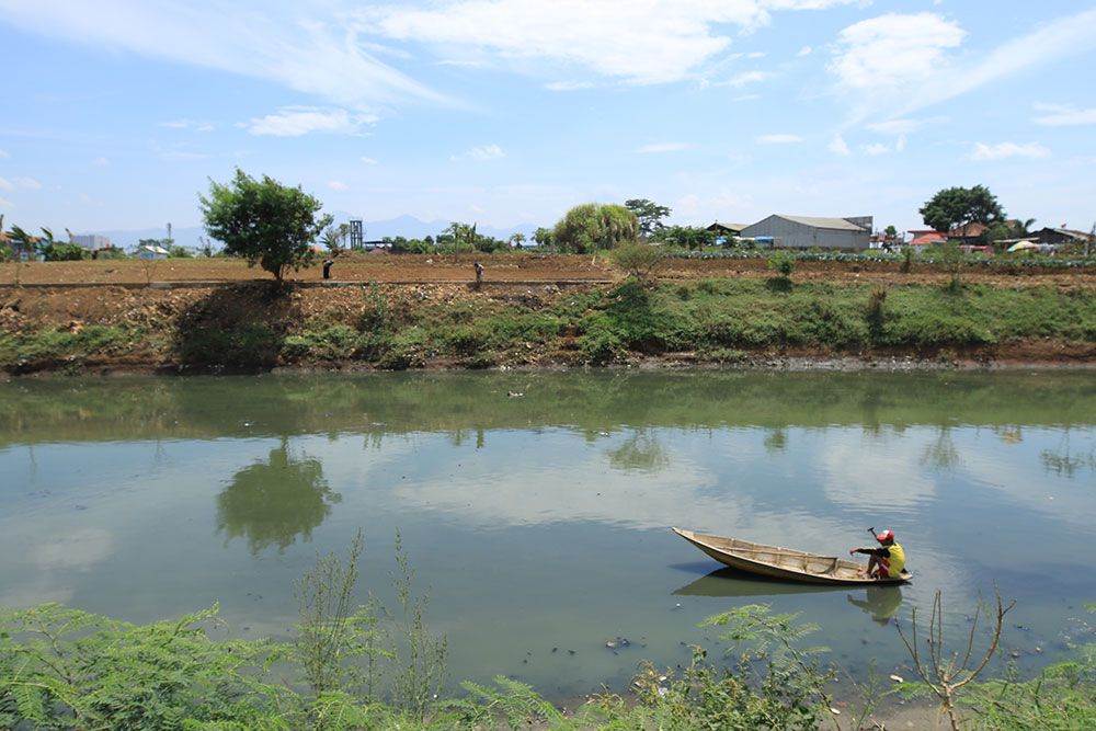 Warga tengah menaiki perahu di Sungai Citarum.