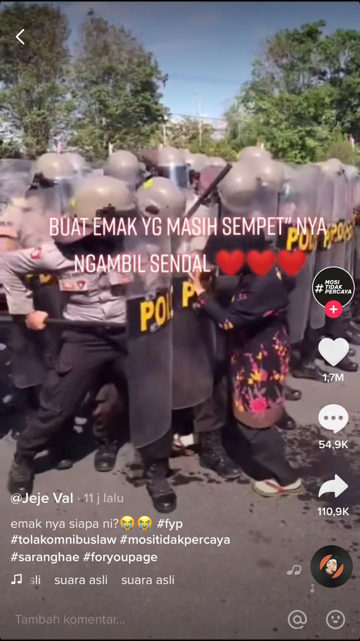 Wanita paruh baya mengambil sendal di kerumunan petugas kepolisian