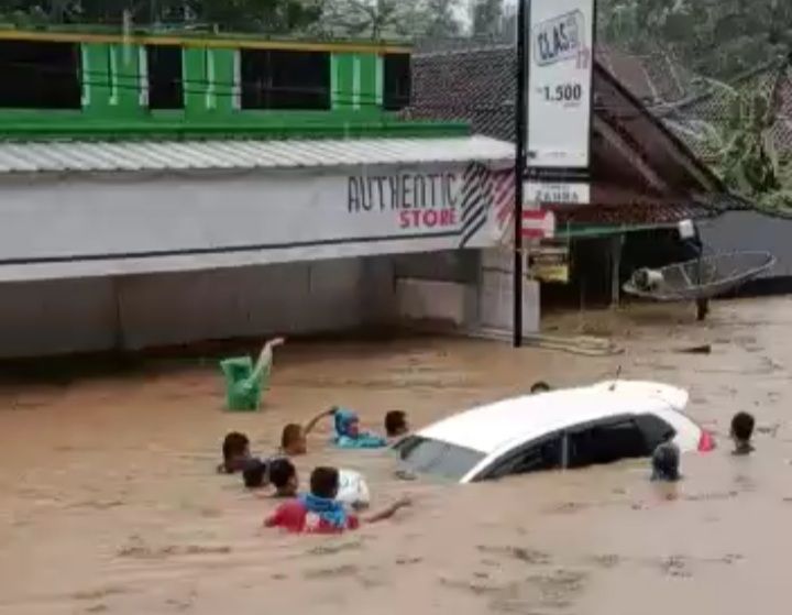 SEJUMLAH warga mencoba mengevakuasi satu unit mobil yang hanyut terseret banjir di Tasikmalaya Selatan.***