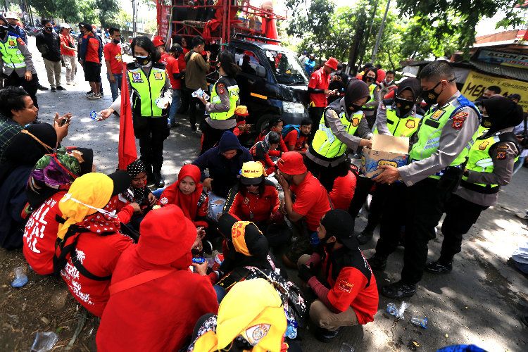 Sejumlah personel dari Satlantas Polresta Bandung, membagikan air minum kemasan kepada sejumlah pengunjuk rasa yang kehausan saat aksi damai terkait penolakan UU Cipta Kerja Omnibus Law di jalan simpang Cileunyi, Kabupaten Bandung, Selasa, 20 Oktober 2020.