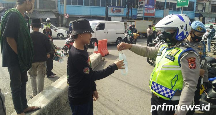 Kasat Lantas Polresta Bandung, Kompol Erik Bangun Prakasa (kiri) membagikan masker kepada anak-anak di Rancaekek, Kabupaten Bandung pada Selasa 27 Oktober 2020.*