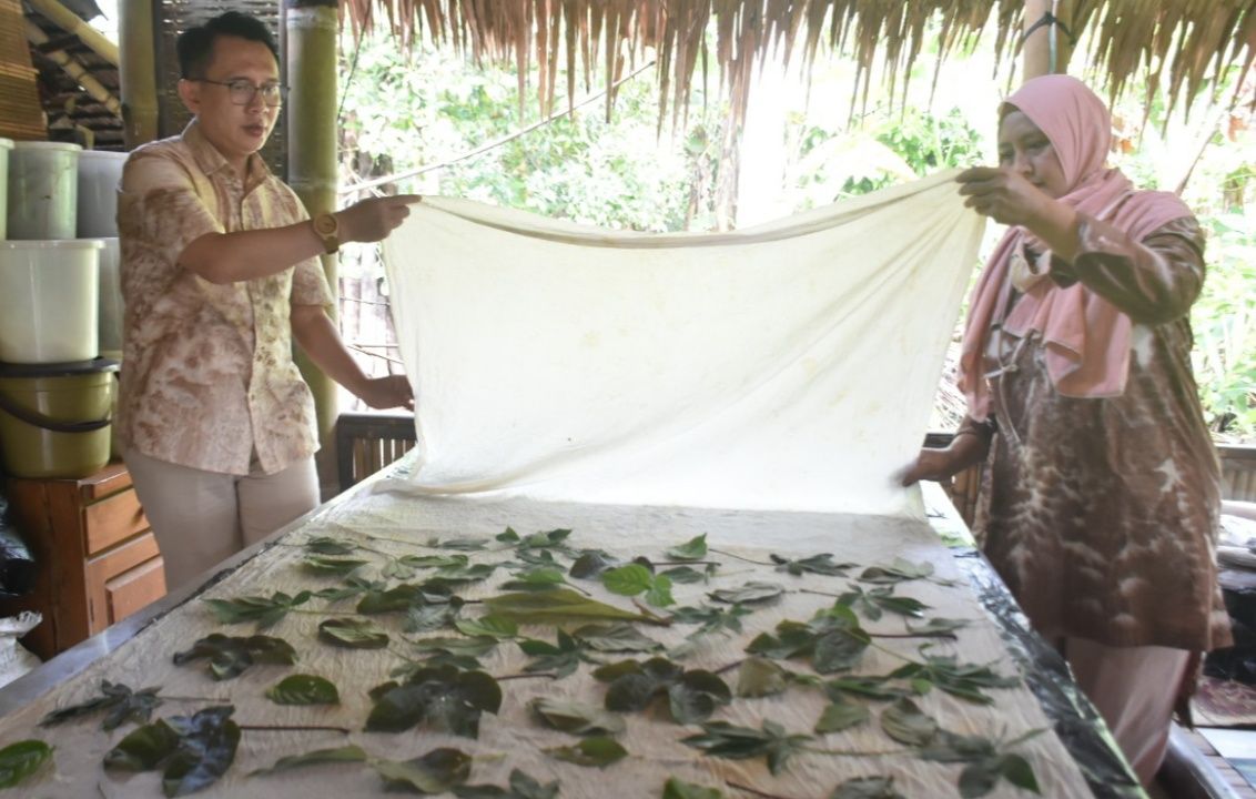 Elin memperagakan cara membuat batik dahon berbahan kain dan daun-daunan.