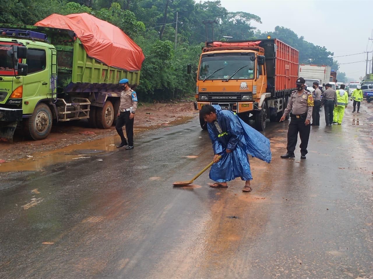 Warga bersama petugas Polsek Cileungsi membersihkan tumpahan proyek galian tanah di Jalan Raya Narogong, Cileungsi, Kabupaten Bogor, Kamis 5 November 2020.*