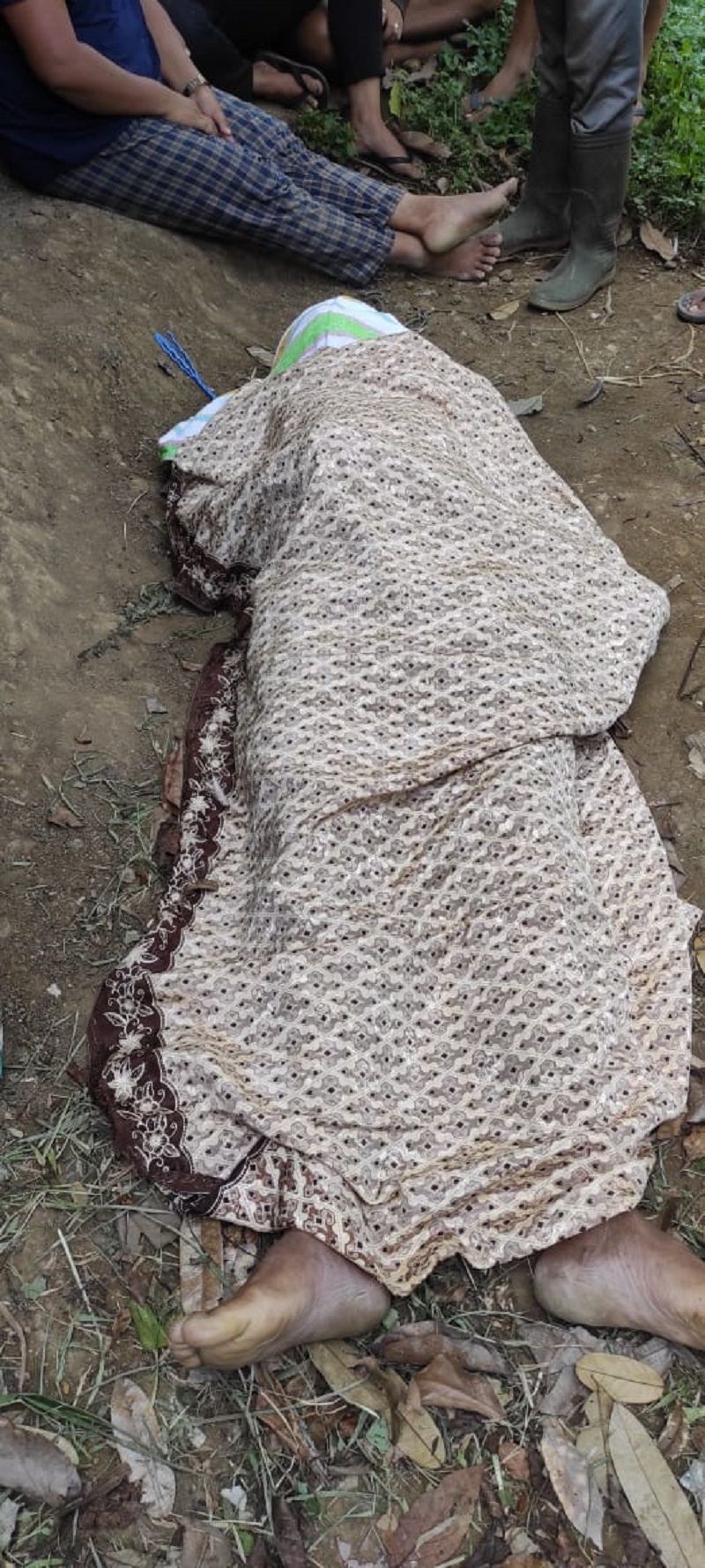 Jenasah Made ditutupi kain saat hendak dibawa ke Puskesma setelah ditemukan gantung diri dengan seutas tali biru di pondok kandang sapi Minggu 22 November 2020