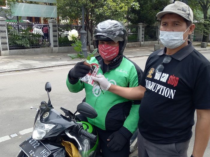 Ketua Jurnalis Hukum Bandung (JHB), Suyono membagikan bunga dan stiker ke pengguna jalan dalam rangka Hari Antikorupsi Sedunia, Rabu, 9 Desember 2020. (Lucky M Lukman/Galamedia)