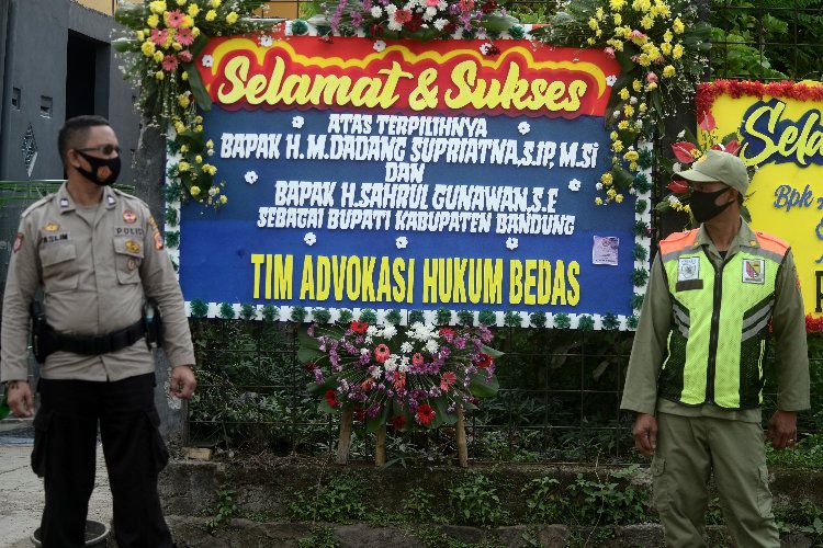 Personel Polresta Bandung dibantu linmas berjaga di depan kediaman calon Bupati Bandung periode 2021-2026, Dadang Supriatna, di jalan Sapan, Desa Tegal luar, Bojongsoang, Kabupaten Bandung, Jumat 11 Desember 2020.