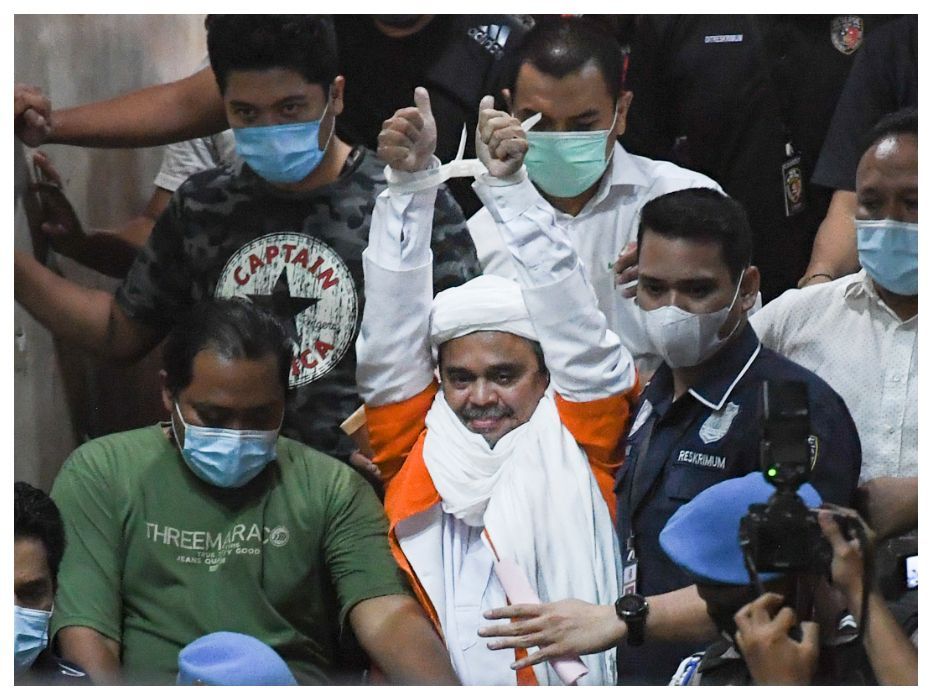 Imam Besar Front Pembela Islam (FPI) Habib Rizieq Shihab (tengah) berjalan menuju mobil tahanan usai diperiksa di Mapolda Metro Jaya, Jakarta, Minggu 13 Desember 2020 dini hari WIB.