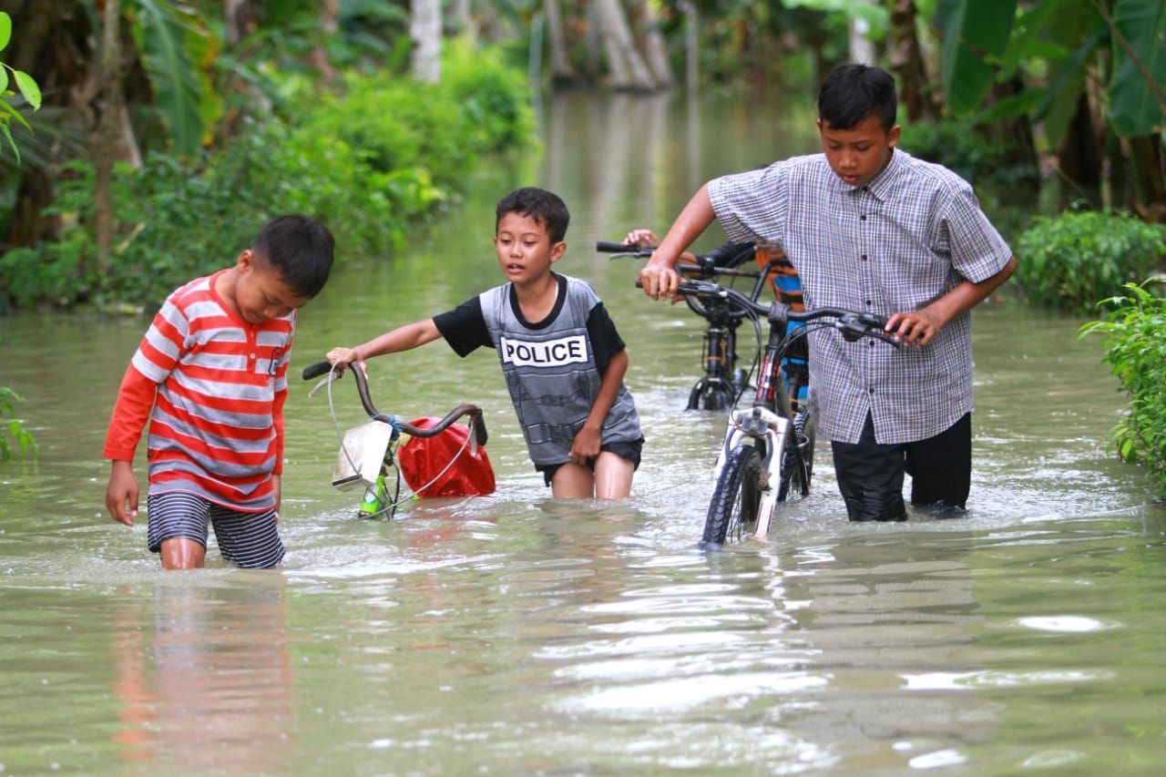 Anak-anak menuntun sepeda di tengah banjir yang melanda desa Wironatan, kecamatan Butuh Purworejo.