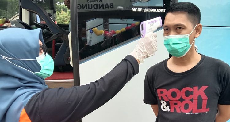  Petugas Dinas Kesehatan Kabupaten Bandung memeriksa suhu tubuh penumpang bus yang hendak berwisata ke Kabupaten Bandung di Gerbang Tol Soroja, Sabtu 26 Desember 2020. 