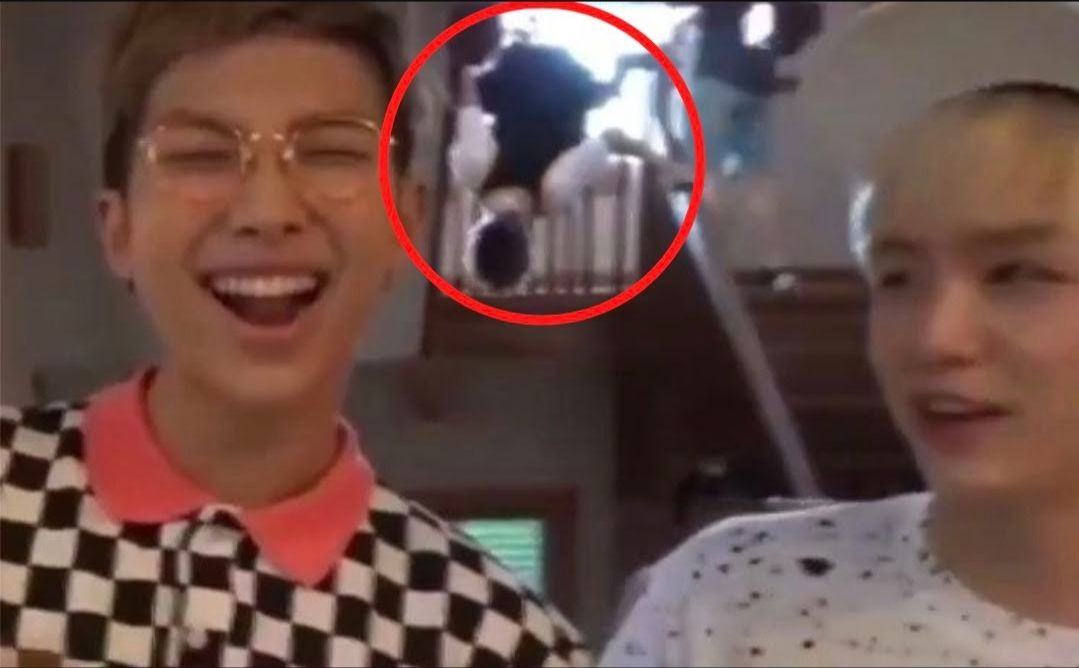 Jungkook tergantung di pagar tangga saat RM dan Suga berinteraksi di depan kamera./theqoo