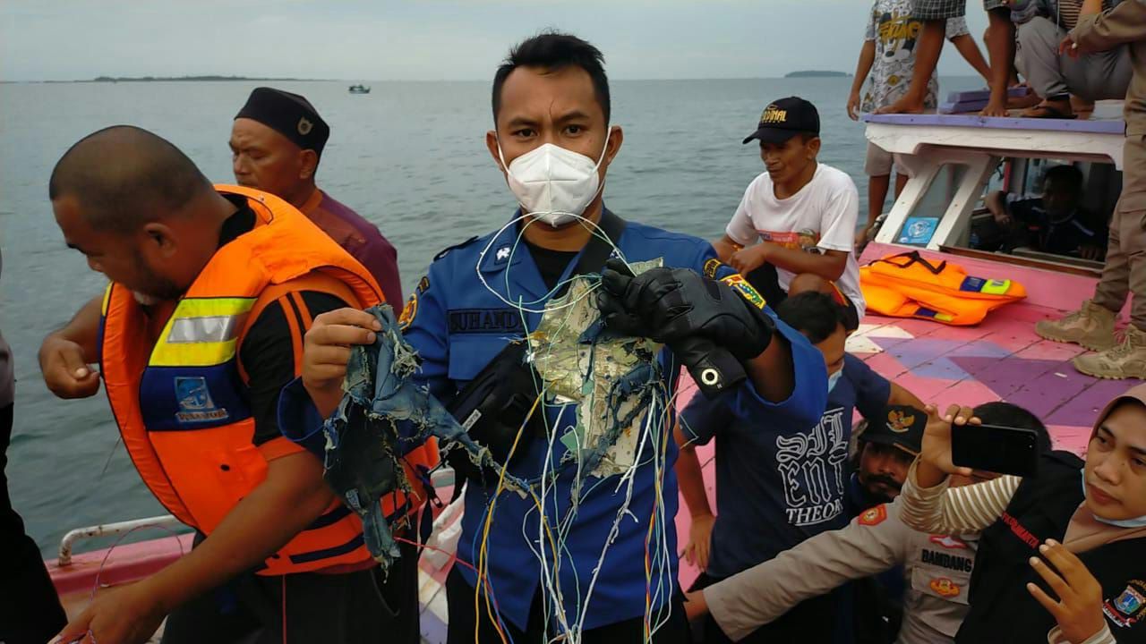 warga memperlihatkan puing yang diduga milik pesawat Sriwijaya yang jatuh