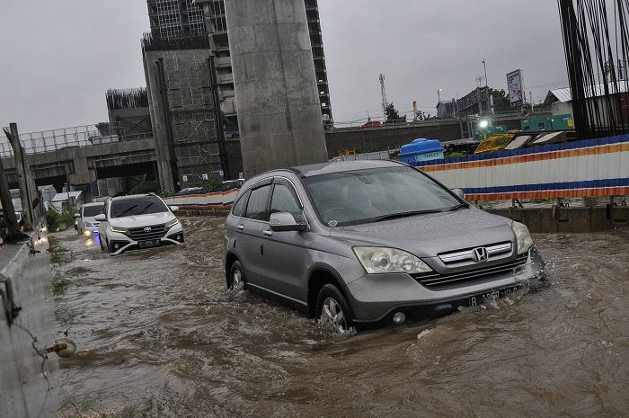 Sejumlah kendaraan melintasi banjir yang menggenangi akses jalan menuju gerbang tol Jakarta-Cikampek, di Jatibening, Bekasi, Jawa Barat.