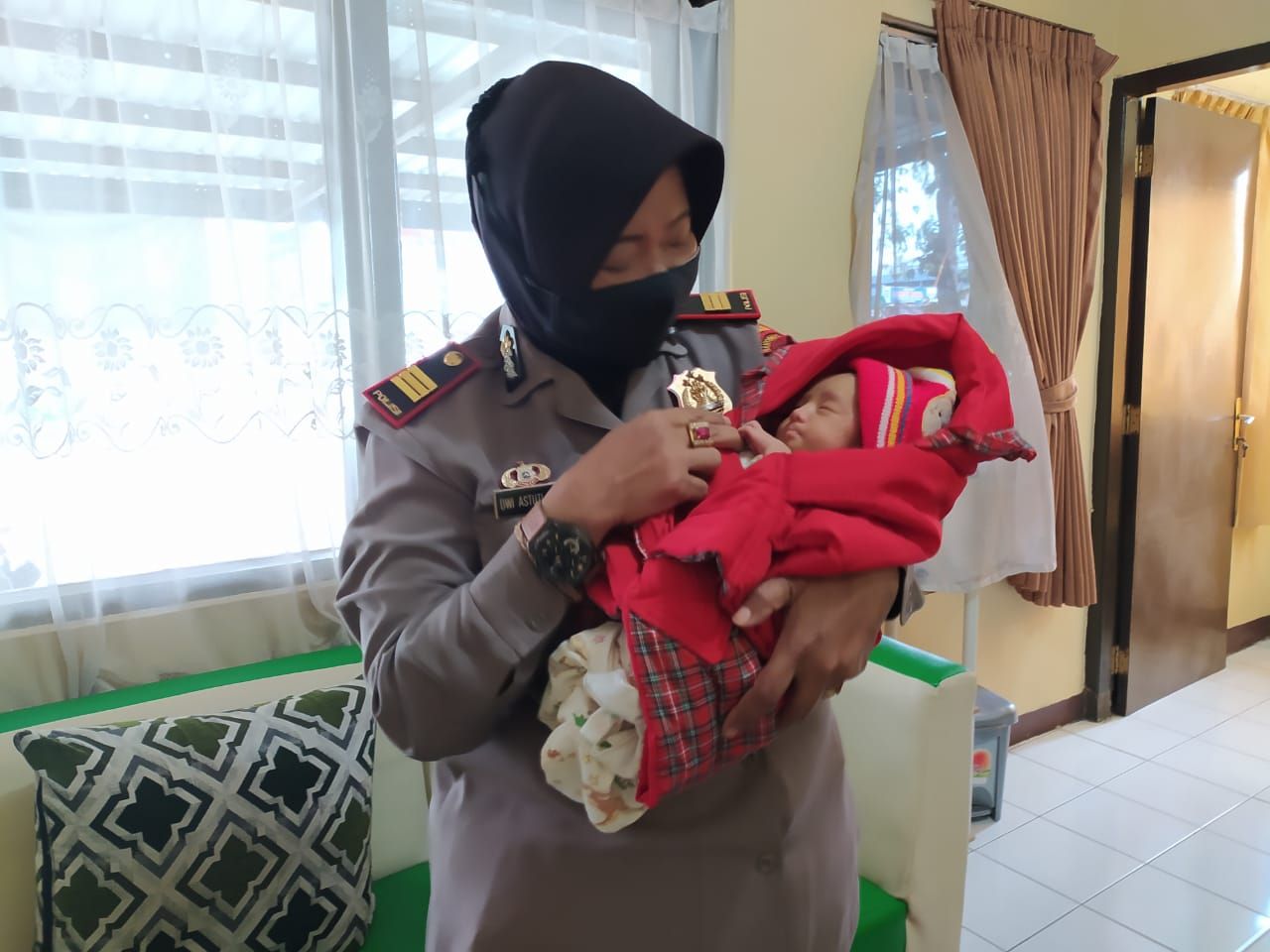 Kapoksek Kalibagor AKP Ratna Dwi Astuti menggendong bayi yang ditemukan warga Desa Pekaja, Kecamatan Kalibagor di teras rumahnya, Sabtu dini hari 20 Februari 2021.