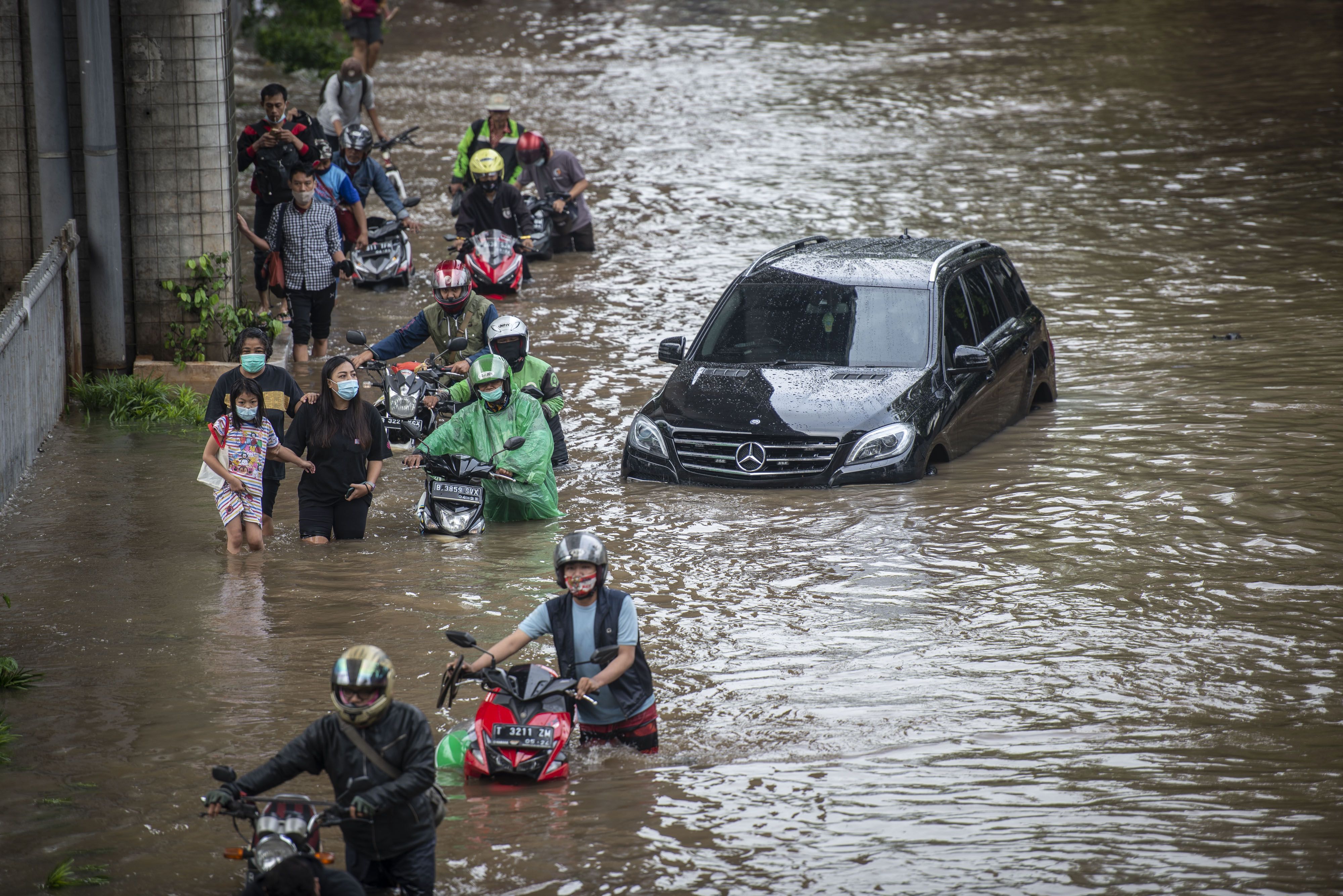 Warga mendorong sepeda motornya melintasi banjir di Jalan Kapten Tendean, Mampang Prapatan, Jakarta, Sabtu 20 Februari 2021. Banjir tersebut disebabkan karena curah hujan tinggi sejak Jumat 19 Februari malam. 