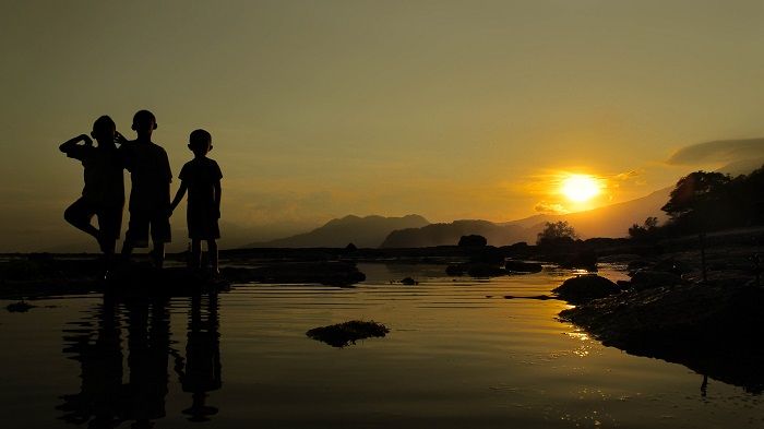 Salah satu spot sunset di Pantai Rako. Tampak anak-anak berdiri menatap kamera saat sunset.