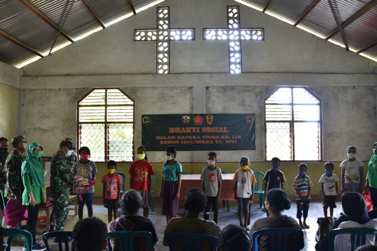Dansatgas TMMD, Letkol. Inf. M. Zulnalendra Utama, membagikan perlengkapan tas dan buku tulis bagi anak-anak sekolah