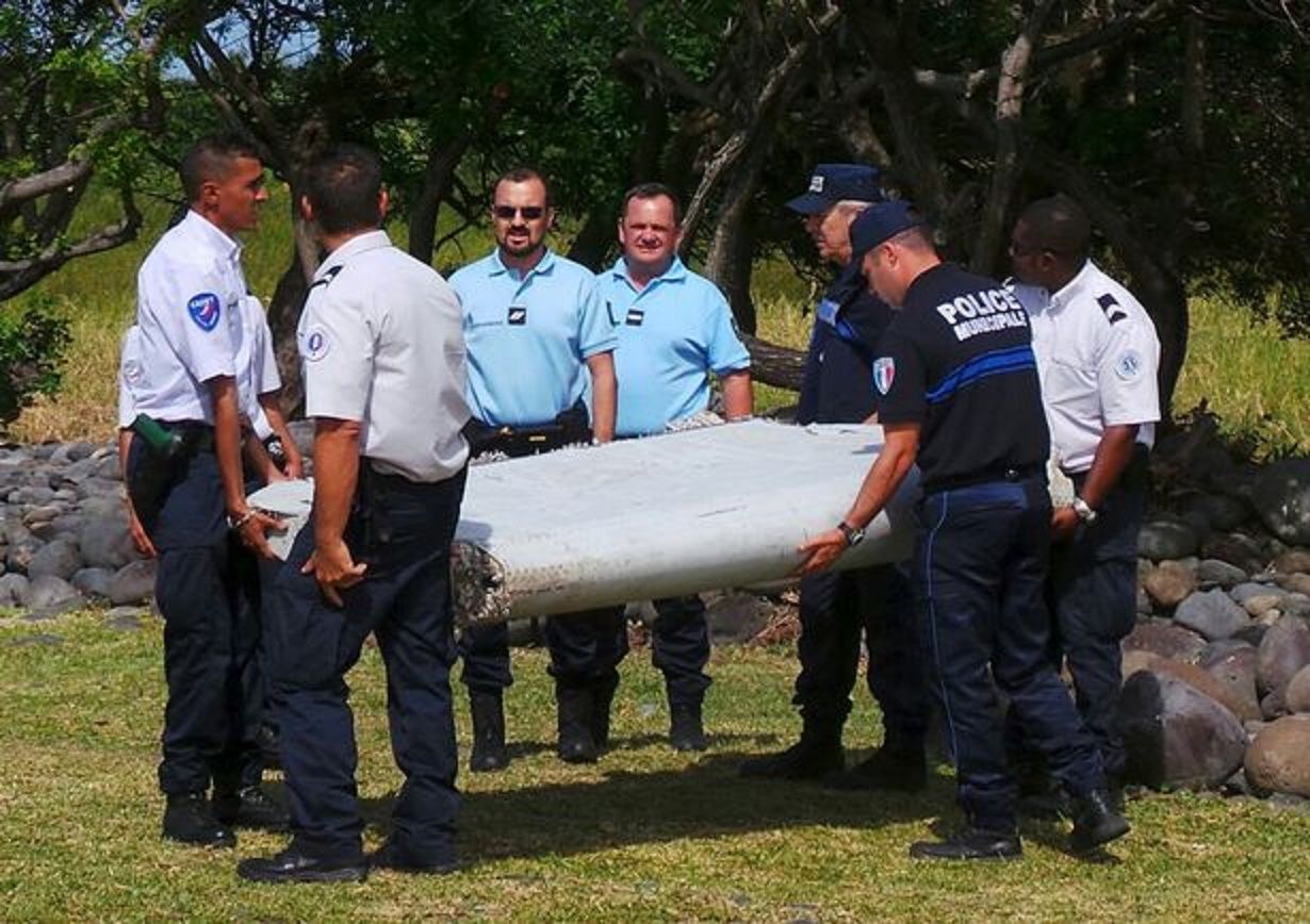 Pihak berwenang membawa potongan besar puing pesawat yang ditemukan di pantai pada tahun 2015.