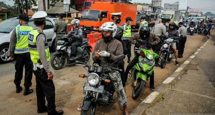 Ilustrasi petugas memberhentikan kendaraan bermotor di titik penyekatan larangan mudik di Jatinangor, Jawa Barat.*  