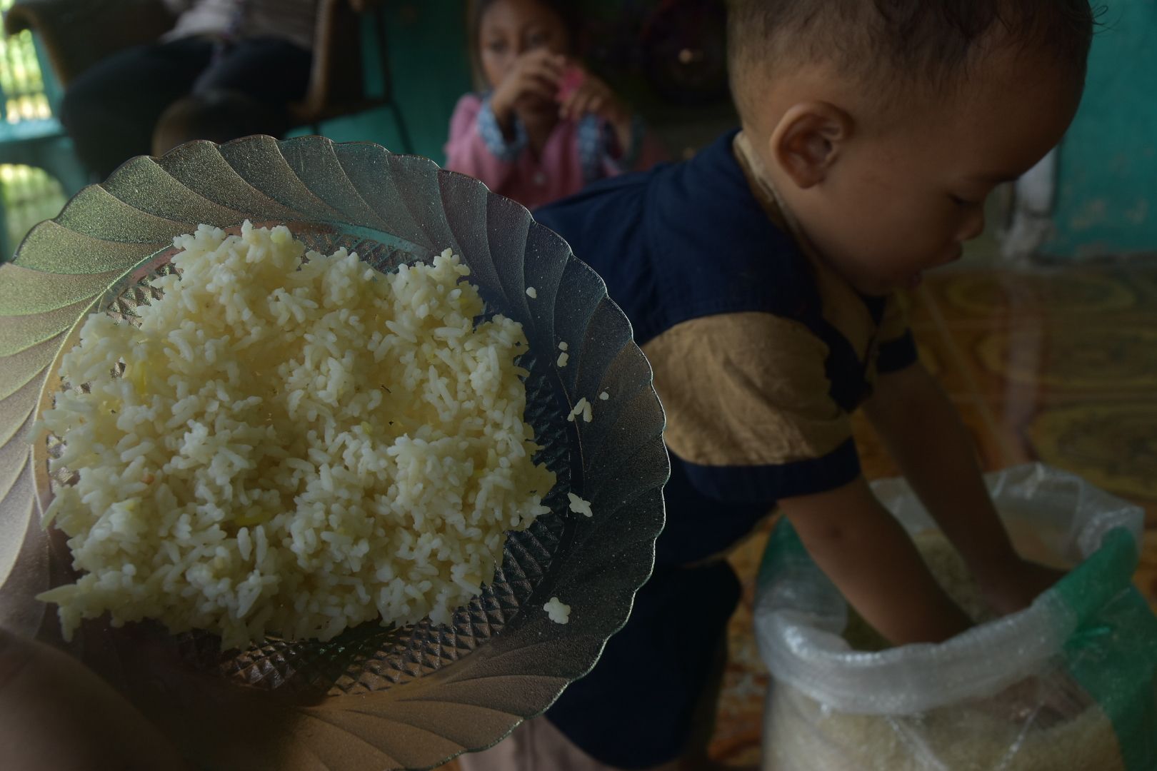 Warga menunjukkan nasi yang dimasak dari beras bansos yang kuning dan busuk.