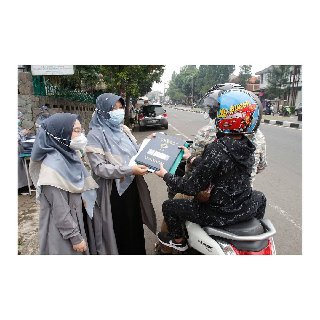Seorang siswa mengambil rapor tanpa turun dari kendaraan, di SD Darul Hikam, Jalan Juanda, Kota Bandung, Selasa, 15 Juni 2021. Pihak sekolah melakukan pembagian rapor secara drive thru supaya menghindari kerumunan dengan tetap mematuhi Prokes Covid-19. 