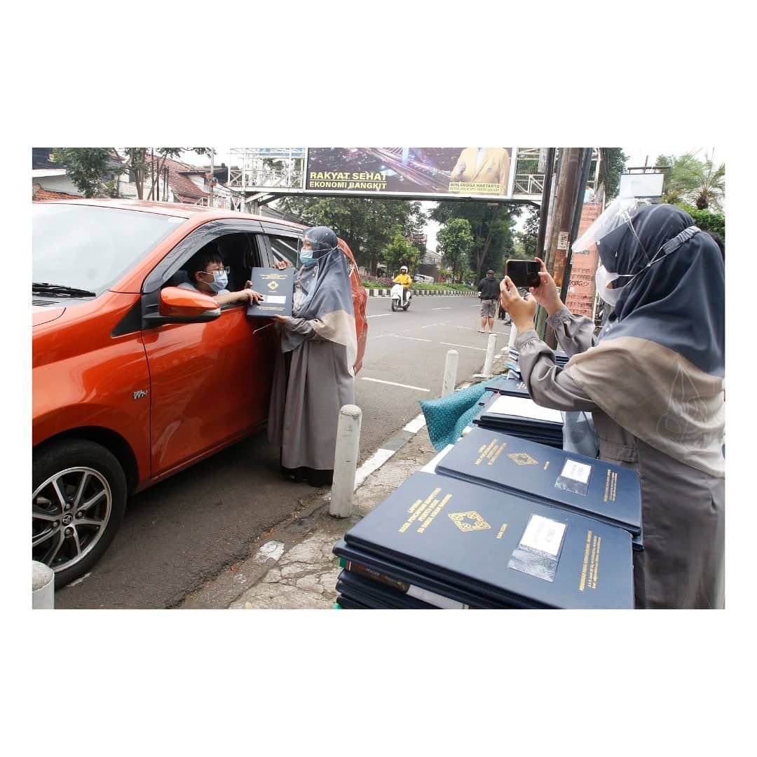 Seorang siswa mengambil rapor tanpa turun dari kendaraan, di SD Darul Hikam, Jalan Juanda, Kota Bandung, Selasa, 15 Juni 2021. Pihak sekolah melakukan pembagian rapor secara drive thru supaya menghindari kerumunan dengan tetap mematuhi Prokes Covid-19. 