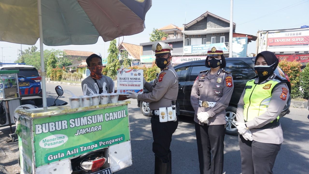 Kasat Lantas Polresta Bandung, Kompol Rislam Harfia saat memberikan bantuan sembako kepada pedagang yang terdampak PPKM Darurat di Kabupaten Bandung, Jumat 16 Juli 2021