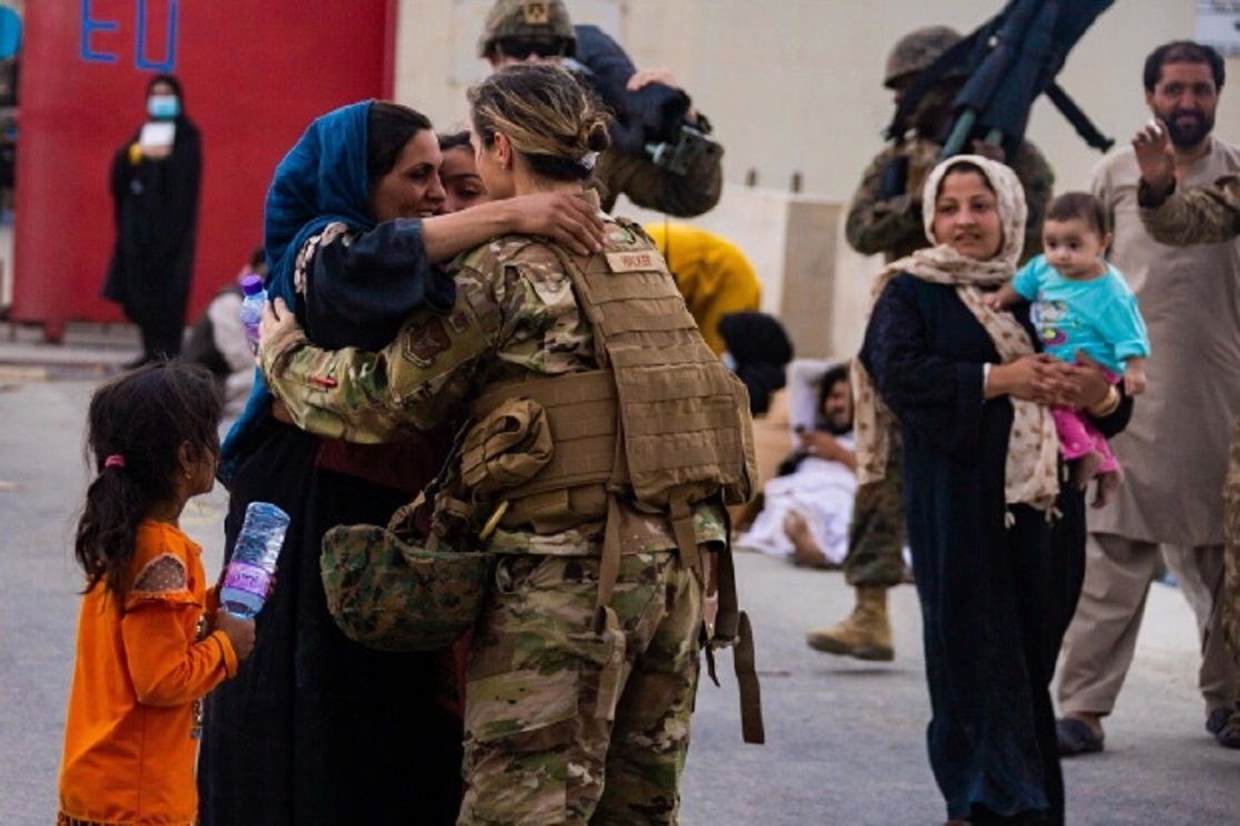 Seorang Penerbang AS memeluk seorang ibu setelah membantu menyatukan kembali keluarga mereka.  