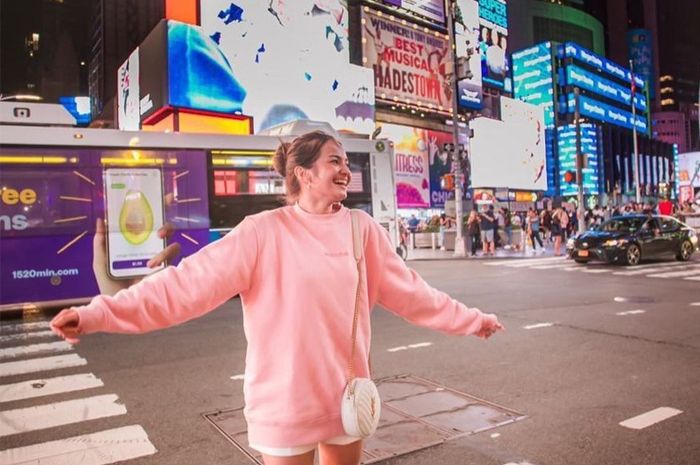 Senyum manis Enzy Storia dengan pemandangan indah latar belakang Time Square, New York.